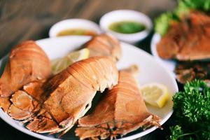 verse pantoffelkreeft met platte kop gekookt koken met peterselie rozemarijn in het visrestaurant, platte kreeftgarnalen geserveerd op een witte plaat en zeevruchtensaus, rotskreeft moreton bay bug foto