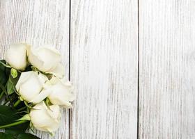 witte rozen op een houten tafel foto