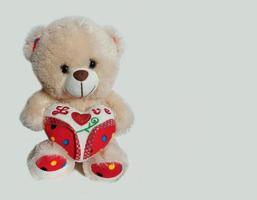 teddybeer met een hart op een grijze achtergrond met plaats voor tekst. banner, Valentijnsdag, liefde, speelgoed, cadeau. foto