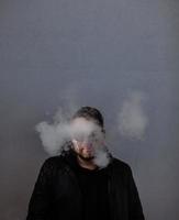 man in een leren jas staat in een rookwolk foto