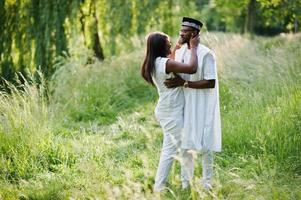 zwart afrikaans paar verliefd zoenen in groen park op zonsondergang foto