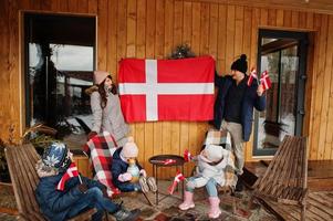 familie met denemarken vlaggen in de buurt van ze houten huis. reizen naar scandinavische landen. gelukkigste Deense mensen. foto
