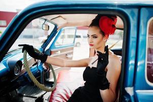 portret van mooie sexy mode meisje model met lichte make-up in retro stijl zittend in vintage auto met een sigaret in de hand. foto