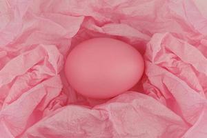 een roze geschilderd paasei op verfrommeld roze inpakpapier. detailopname. foto