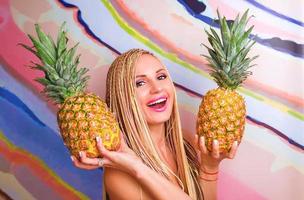 vrouw met Afrikaanse vlechten en met ananas in haar handen in gele jurk foto