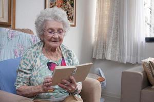 oudere dame die thuis in een stoel zit en een boek leest foto
