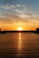 oranje zonsondergang op de rivier met silhouetten foto