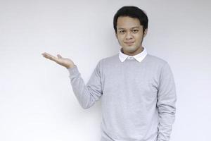 jonge aziatische man is glimlach en blij met met handpunt op lege ruimte foto