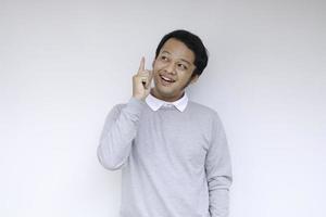 blij en glimlach gezicht met glimlach van jonge aziatische man in wit overhemd met hand punt op boven lege ruimte. foto
