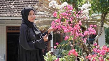 de schoonheid in hijab is tuinieren, bloemen snijden zodat ze netjes in de tuin staan foto