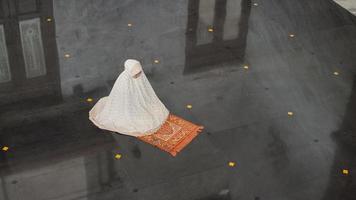 Aziatische moslimvrouw die alleen bidt zonder imam in moskee foto