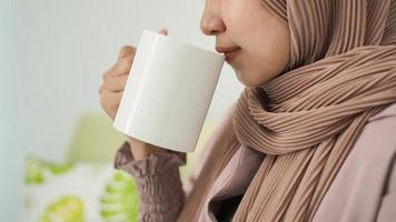 Aziatische vrouw in hijab die thuis van een drankje geniet foto