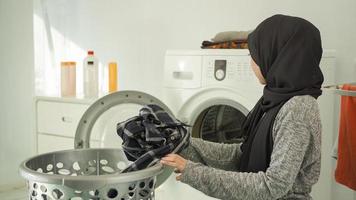 jonge aziatische vrouw die vuile kleren kiest om thuis te wassen foto