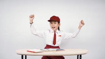 Aziatische basisschool meisje hartstochtelijk studeren geïsoleerd op witte achtergrond foto
