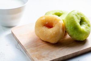 vanille en pandan donut op houten snijplank met kop warme melk. ontbijtconcept. foto