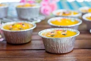 close-up minimale oranje cake met botercrème in folie beker op houten tafel. heerlijke bakkerij in koffie- en theetijden foto