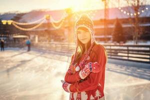 portret van een jonge vrouw op de ijsbaan, een glimlach op zijn gezicht, de zon foto