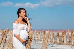 mooie zwangere vrouw in de natuur in witte jurk foto