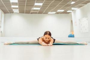 vrouw doet stretching op de mat in de hal zittend op het touw foto