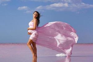 mooie jonge zwangere vrouw genieten van de zon op het strand, roze meer foto