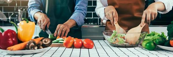 twee jonge aziatische stellen helpen elkaar en genieten van koken in de keuken. foto