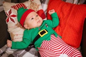 kerstconcept kleine jongen vrolijke elf opzoeken ligt op veelkleurig foto