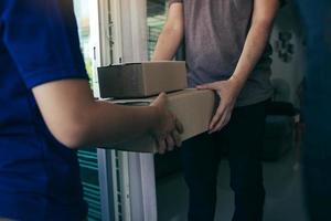close-up van handen vrachtpersoneel levert kartonnen dozen met pakketten aan de hand van de ontvanger. foto