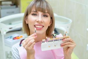 gelukkige vrouw in de tandheelkunde pikt de kleur van tandglazuur op foto