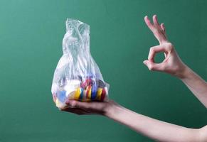 de hand van een vrouw houdt een zak met plastic deksels vast om te recyclen foto