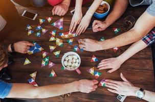 bovenaanzicht creatieve foto van vrienden zitten aan houten tafel. plezier hebben tijdens het spelen van een bordspel