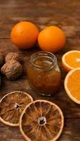 zoete sinaasappeljam of marmelade dessert met walnoten op houten achtergrond foto