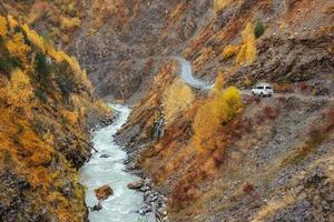 gouden herfstlandschap tussen rocky mountains en luidruchtige rivier in georgië. Europa foto