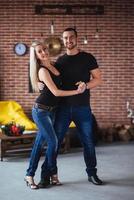 jong koppel dansen latin muziek bachata, merengue, salsa. twee elegantie poseren op café met bakstenen muren foto