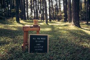 citaat op letterbord en een kopje koffie op houten tafel met buiten groene zomerbos achtergrond, liefde en koffie citaten foto