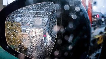 weerspiegeling van de verkeersstroom van de achteruitkijkspiegel van de auto met waterdruppel bij hevige regen foto