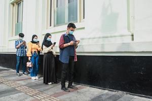 groep jongeren op een rij die sociale afstand houden tegen de verspreiding van het coronavirus of covid-19 pandemische ziekte. nieuw normaal concept. foto