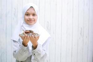 jonge Aziatische moslimvrouw die lacht en dadels op het bord aanbiedt? foto