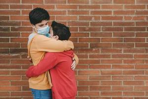 twee vrienden met medisch masker knuffelen na quarantaine door covid-19 foto