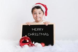 lachende jongen met een schoolbord met Kerstmis foto