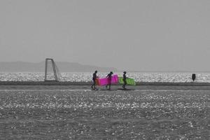 drie mensen zwart en wit met kleurrijke luchtbedden aan zee foto