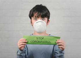 het coronavirus stoppen. kind met groene papel met de tekst stop coronavirus foto