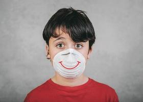 kind met medisch masker voor coronavirus met een getekende glimlach foto