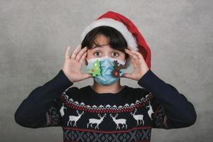 vrolijk kerstfeest, kind met grappig medisch kerstmasker foto