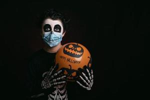 gelukkig halloween, kind met medisch masker in een skeletkostuum met halloween-ballon foto