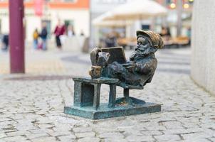 wroclaw, polen, 7 mei 2019 dwerg zit en leest een boek, beroemde bronzen miniatuurkabouter foto