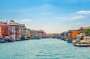 smal waterkanaal met afgemeerde boten en industriële visserijschepen en oude gebouwen aan de kade in chioggia foto