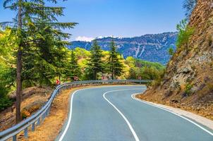 asfalt kronkelige weg in troodos-gebergte met hek langs de weg en bomen foto