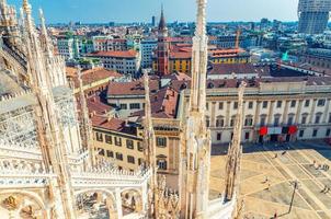 bovenaanzicht vanaf het dak van de beroemde Duomo di Milano kathedraal van witmarmeren beelden en koninklijk paleis palazzo reale foto