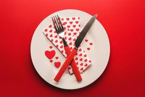 gelukkige valentijnsdag. rood bestek geserveerd op bord voor valentijnsdag. valentijnsdag diner concept foto