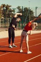 meisje en een jongen doen een warming-up voor sportoefeningen in het schoolstadion foto